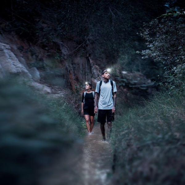 HF4R Signature Headlamp worn by a man and woman hiking along a shaded forest trail at dusk