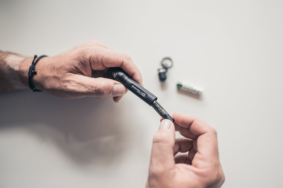 P3R Torch being assembled by hands with small components on a light surface showing Ledlenser’s compact rechargeable torch