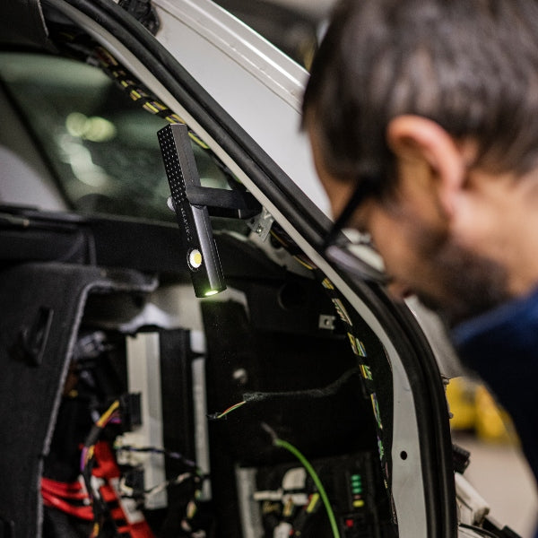 Ledlenser W4R Work Worklight hanging inside a vehicle hood compact black work light with green accent for workshop use