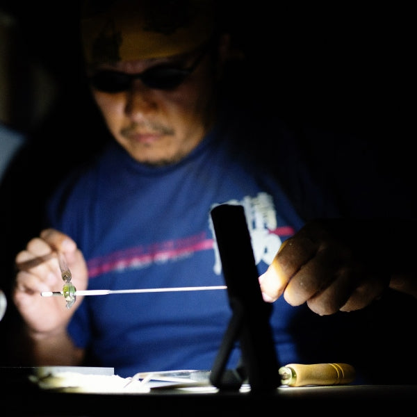 Ledlenser W4R Work Worklight in use at a workstation; person wearing safety glasses adjusts a small light on a work setup in a dim environment