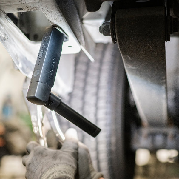 Ledlenser W6R Work Light mounted under a vehicle chassis with its extendable handle visible in the foreground