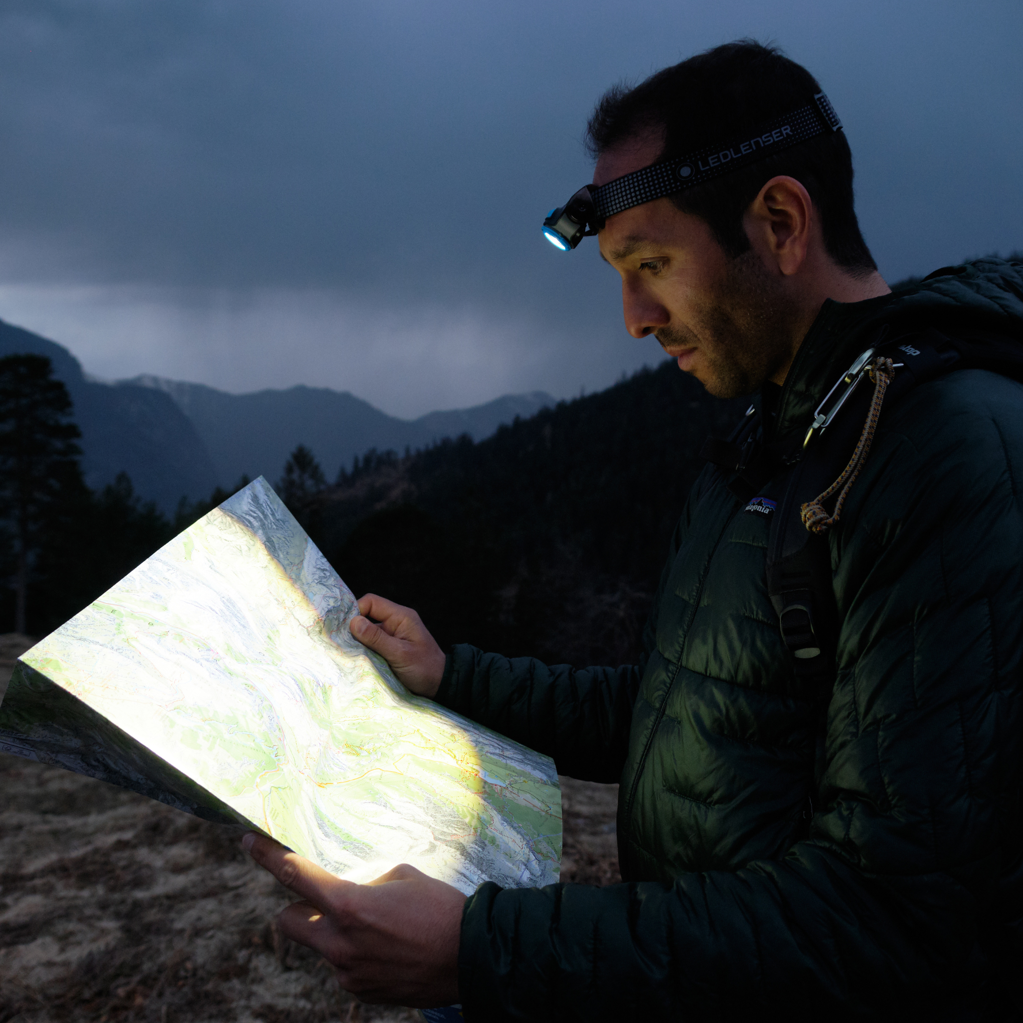 Ledlenser MH5 Powercase Combo headlamp and charging case worn by a man outdoors at night illuminating a map