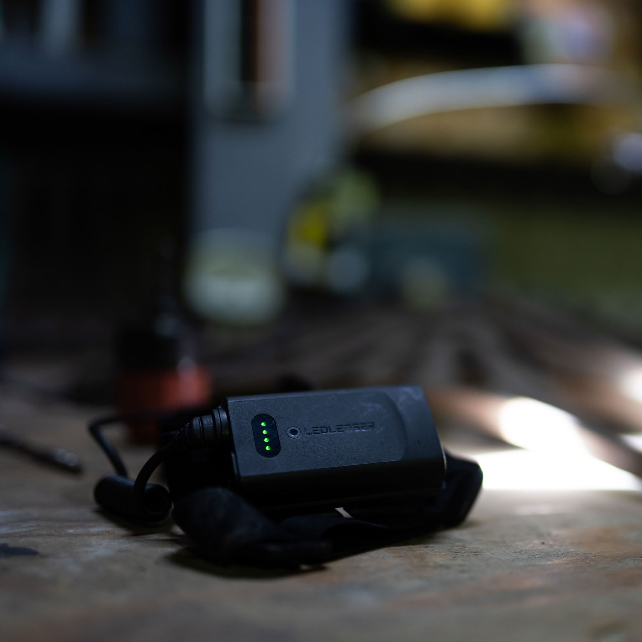Ledlenser H5R Core Headlamp charging unit on a wooden table with green status LEDs visible on the black housing