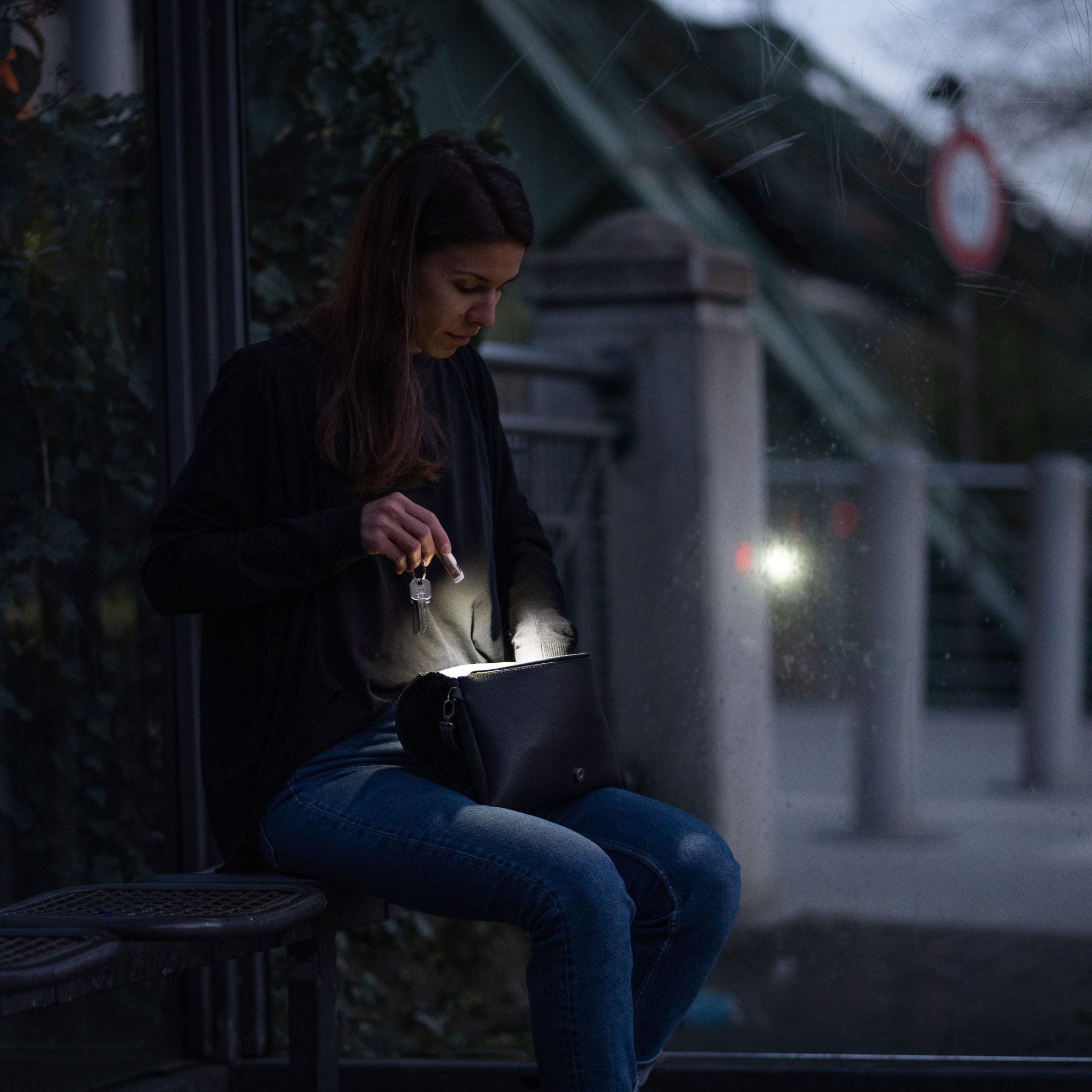 Ledlenser K4R Keychain Light being used to illuminate a handbag on a woman's lap while sitting on a bench at night