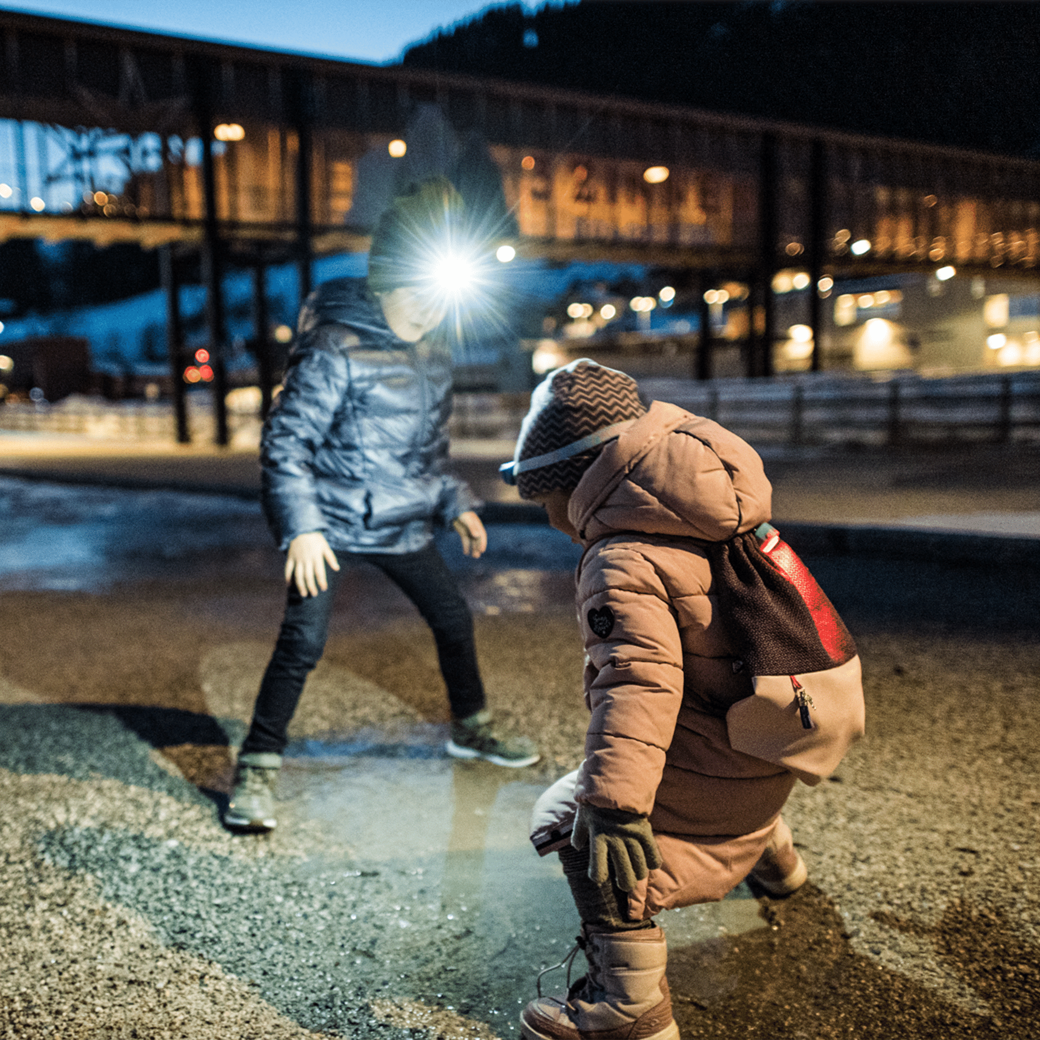 Kidled4R Headlamp worn by child in brown jacket at night with bright beam visible outdoor scene