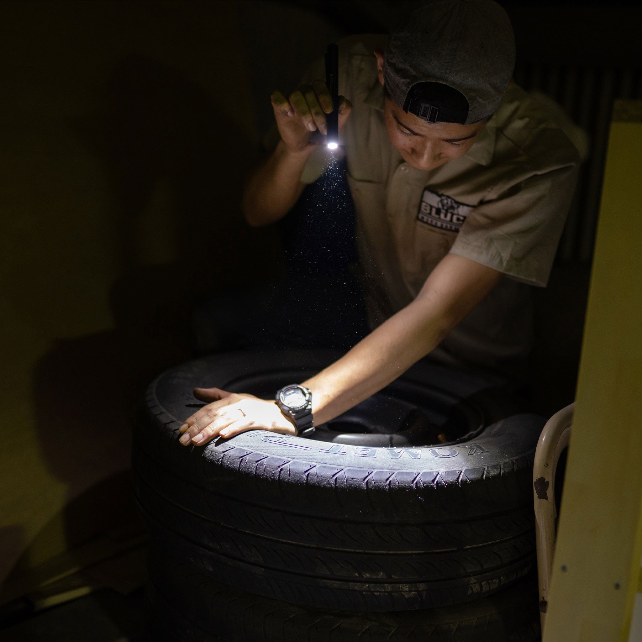 Ledlenser P4R Core Torch in use by a worker illuminating a tire in a dim workshop