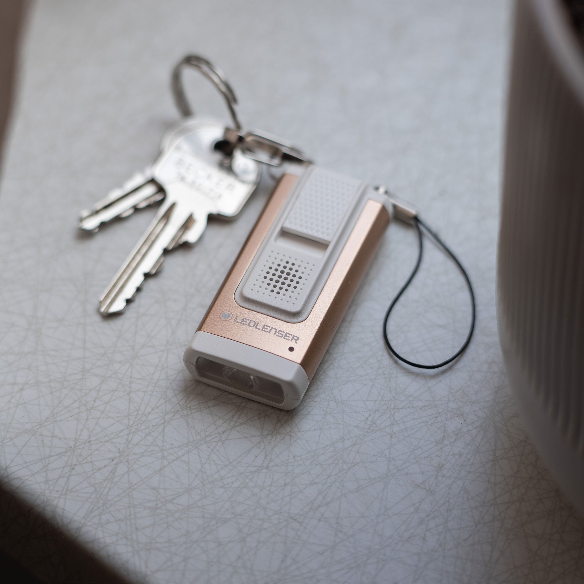 Ledlenser K6R Safety Keychain Light compact rose gold and grey rechargeable keychain torch with metal ring and keys nearby