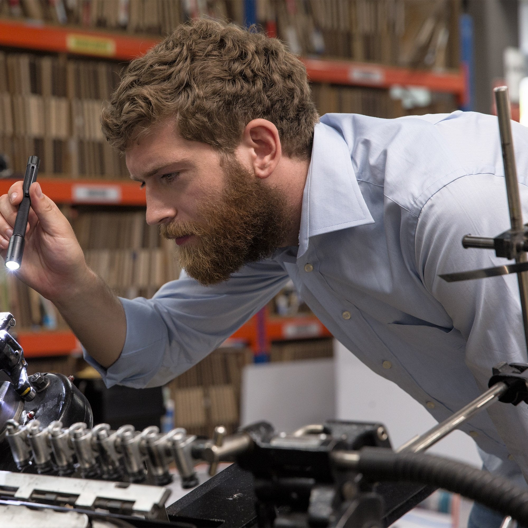 Ledlenser i6 Battery Operated Pen Light held by a man in a workshop inspecting mechanical components