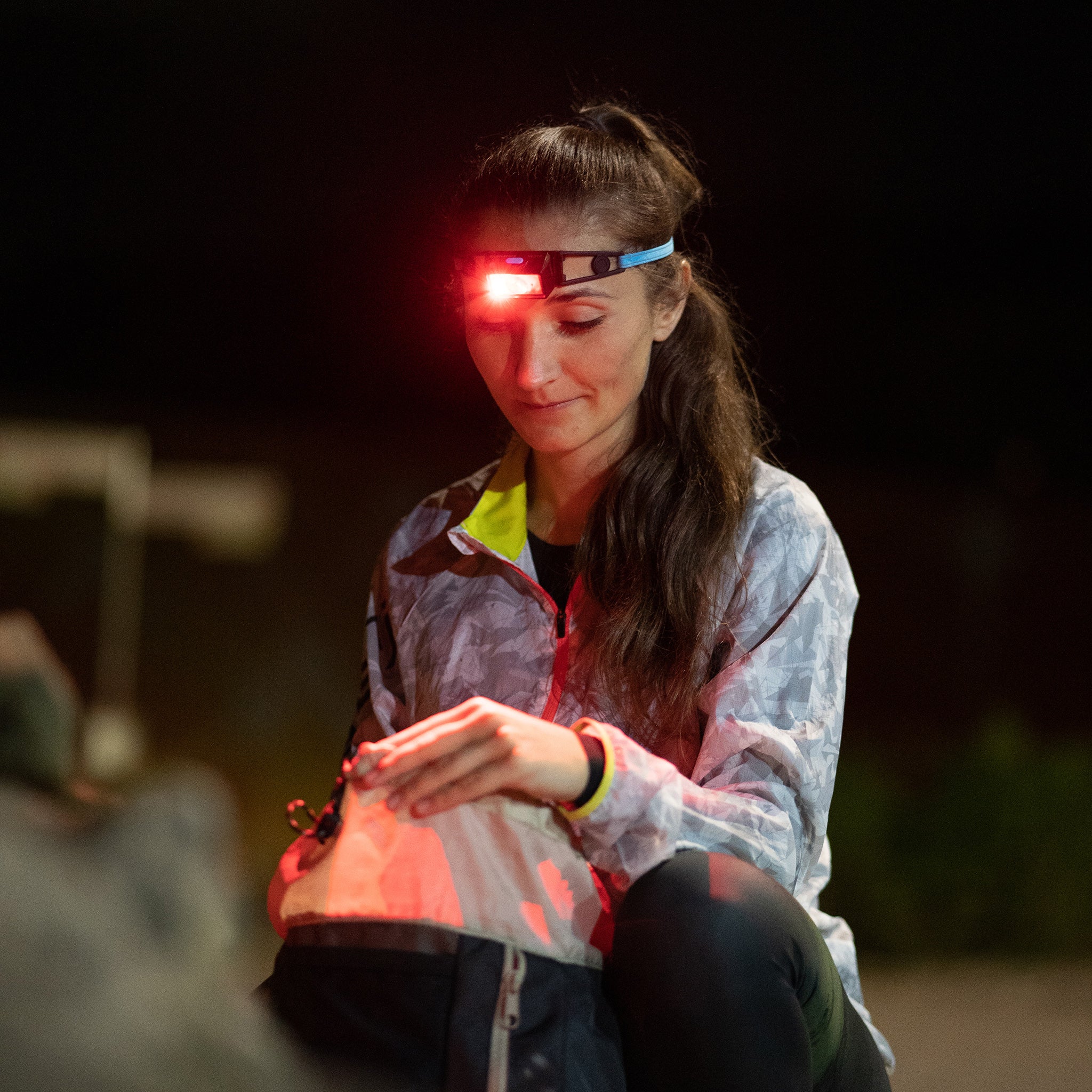 NEO1R Headlamp worn by a woman at night with a red beam outdoors head mounted lighting in use