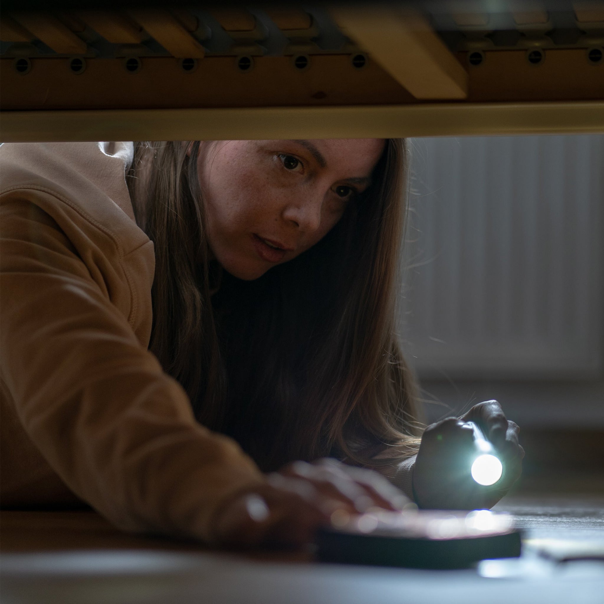 P5R Core Torch held under a table by a person compact handheld flashlight with beam on the floor