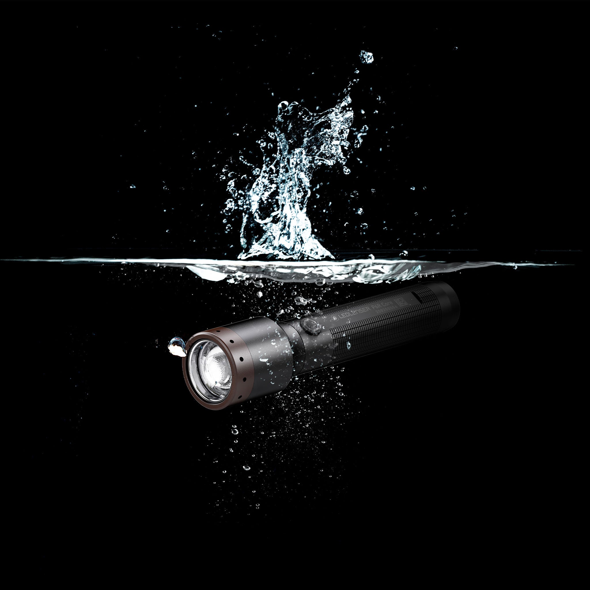Ledlenser P6R Core Torch horizontal black cylindrical flashlight with brown bezel submerged in water with splashes