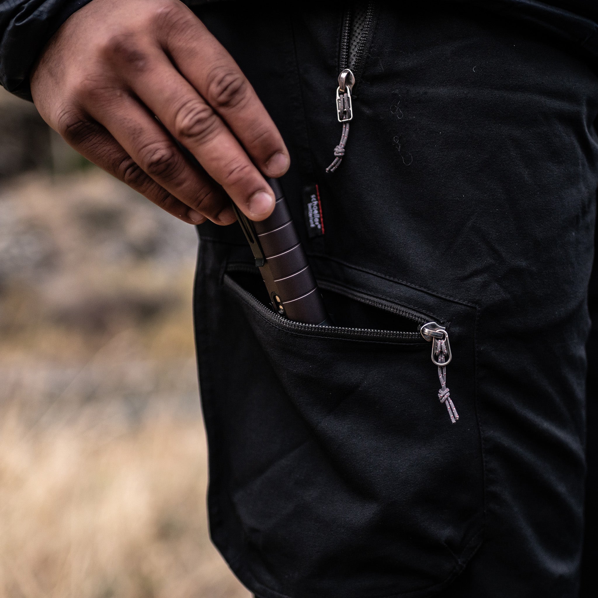 Ledlenser P7R Signature Torch being held and placed into the internal pocket of a black outdoor jacket