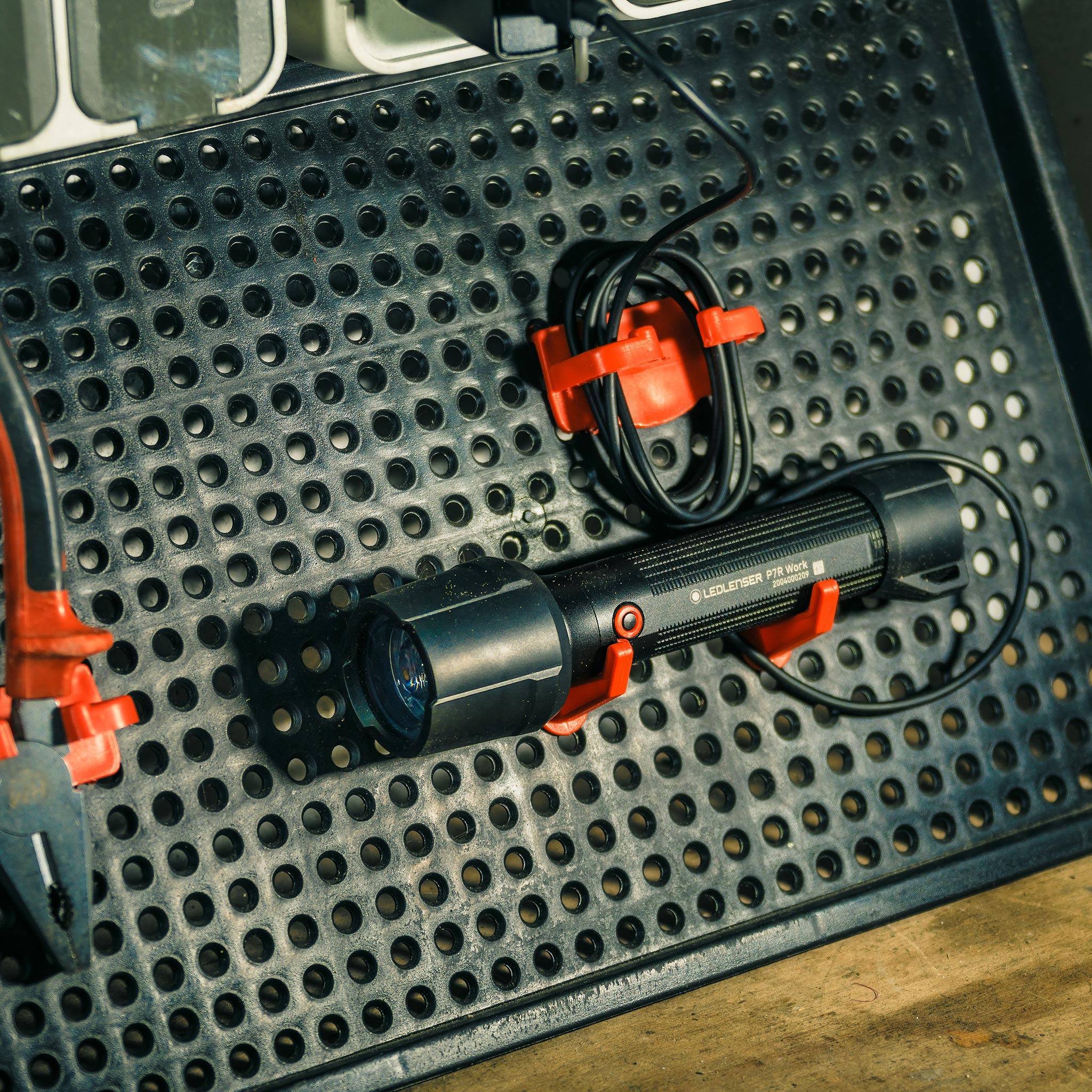 P7R Work Torch mounted on a perforated metal work surface with red mounting clips and a coiled cable