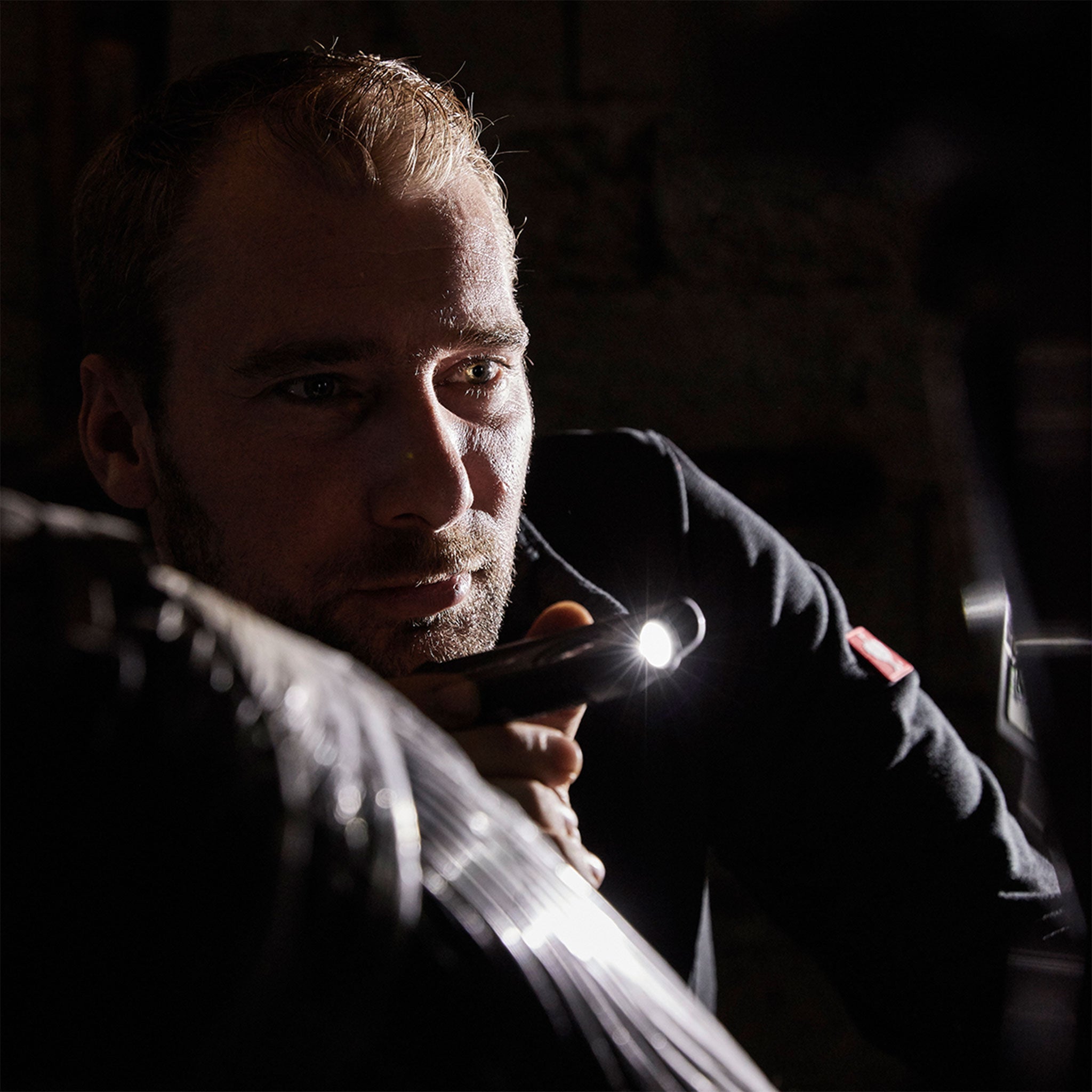 iF2R Spotlight handheld LED torch held by a man in a dark setting with the compact light on