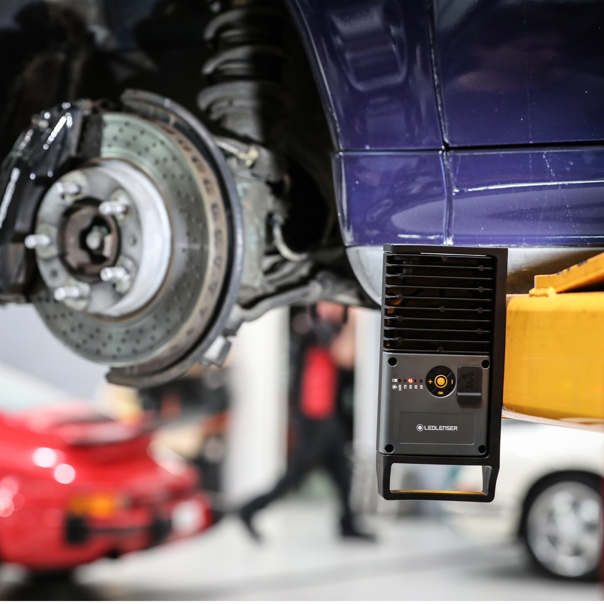 iF4R Spotlight mounted under a car on a lift black compact rechargeable spotlight with control panel