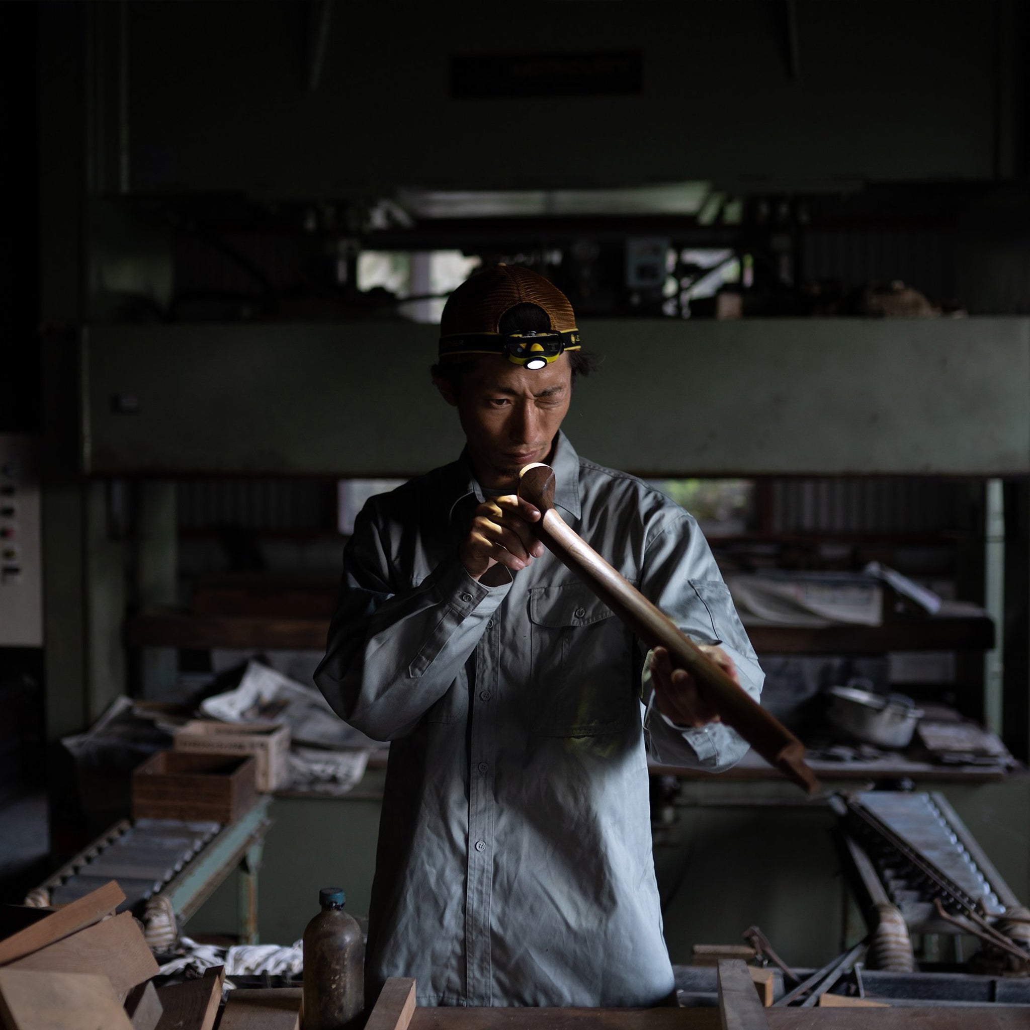 iH9R Headlamp worn by a craftsman in a dim workshop headlamp active as he inspects a wooden tube