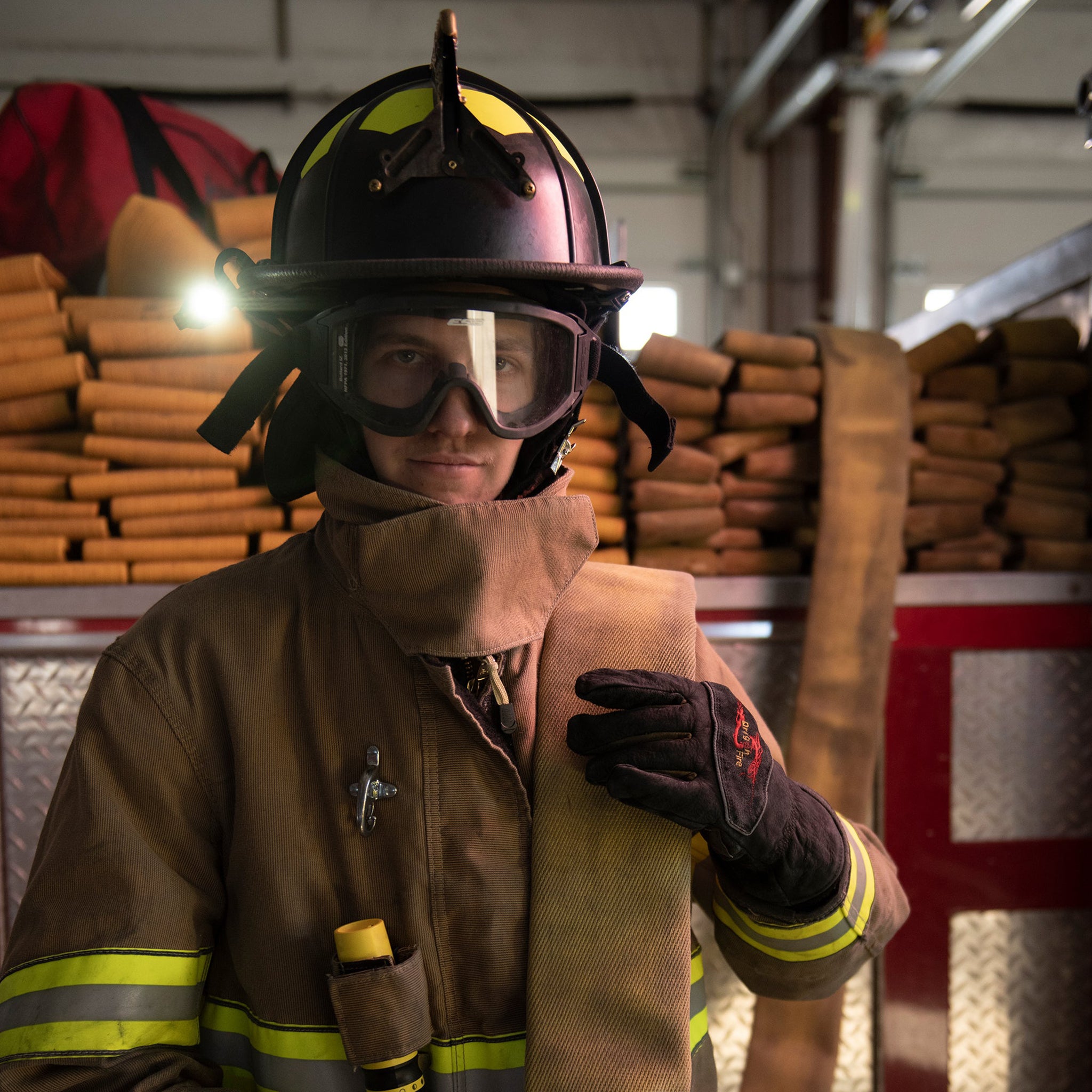Ledlenser iL4 Torch in use by a firefighter wearing helmet and protective gear inside a station with stacked hoses in the background