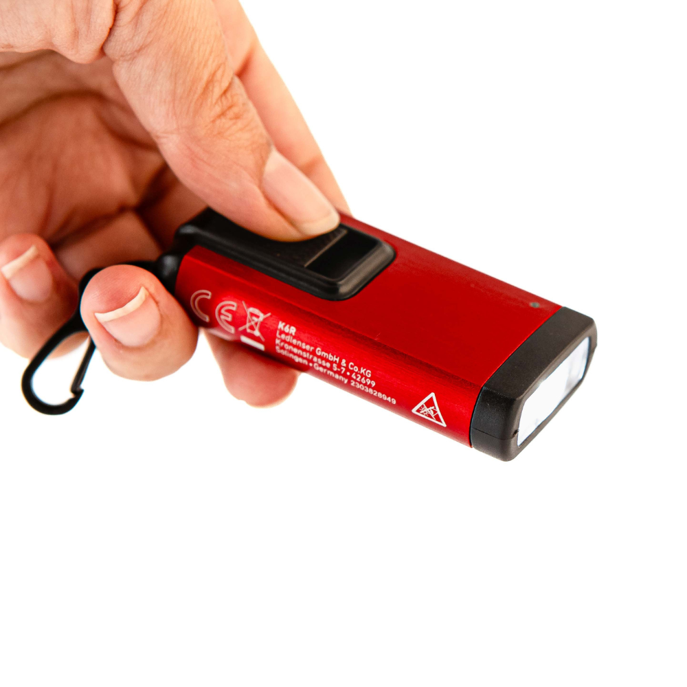 Limited Edition Red K6R Keychain Light held in hand; compact red LED torch with black head and hanging loop