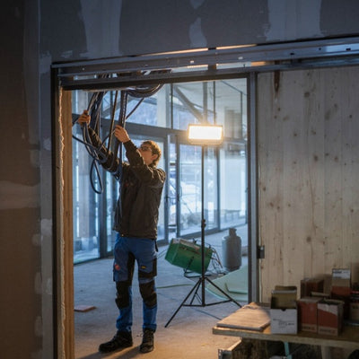 Ledlenser AF12C Work Floodlight on a tripod in a construction site worker wiring cables beside the illuminated portable light