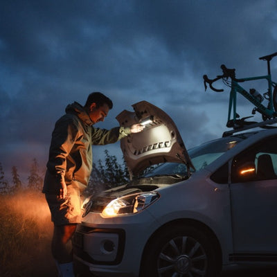 Ledlenser AF2R Work Area Light in use at dusk with a person inspecting a car engine under the hood