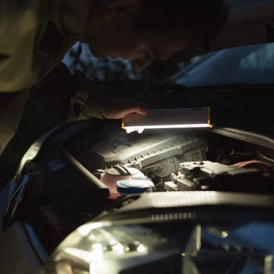 Ledlenser AF2R Work Area Light in use under a car hood illuminating the engine bay with a slim rectangular rechargeable light