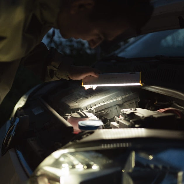 Ledlenser AF2R Work Area Light in use under a car hood illuminating the engine bay with a slim rectangular rechargeable light