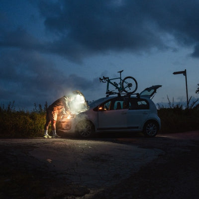 Ledlenser AF2R Work Area Light in use under a car hood at twilight illuminating the engine bay with a bike mounted on the roof
