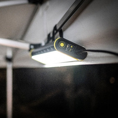 Ledlenser AT10C Work Task Light mounted under a ceiling bar black with yellow trim emitting bright white light downward