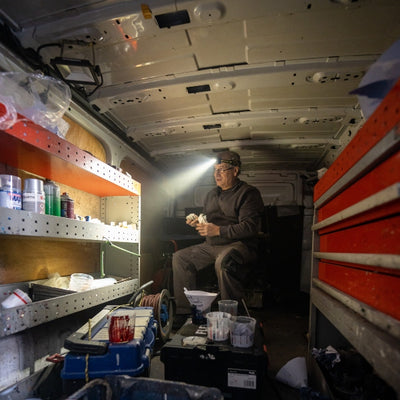 HF6R Work Headlamp in use inside a van; a man wearing the headlamp illuminates tools and workspace