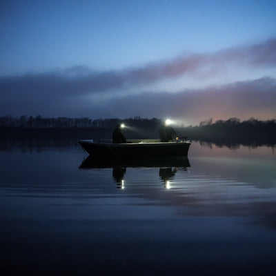 HF8R Core Headlamp worn by two people on a boat at dusk with headlamp beams illuminating the water