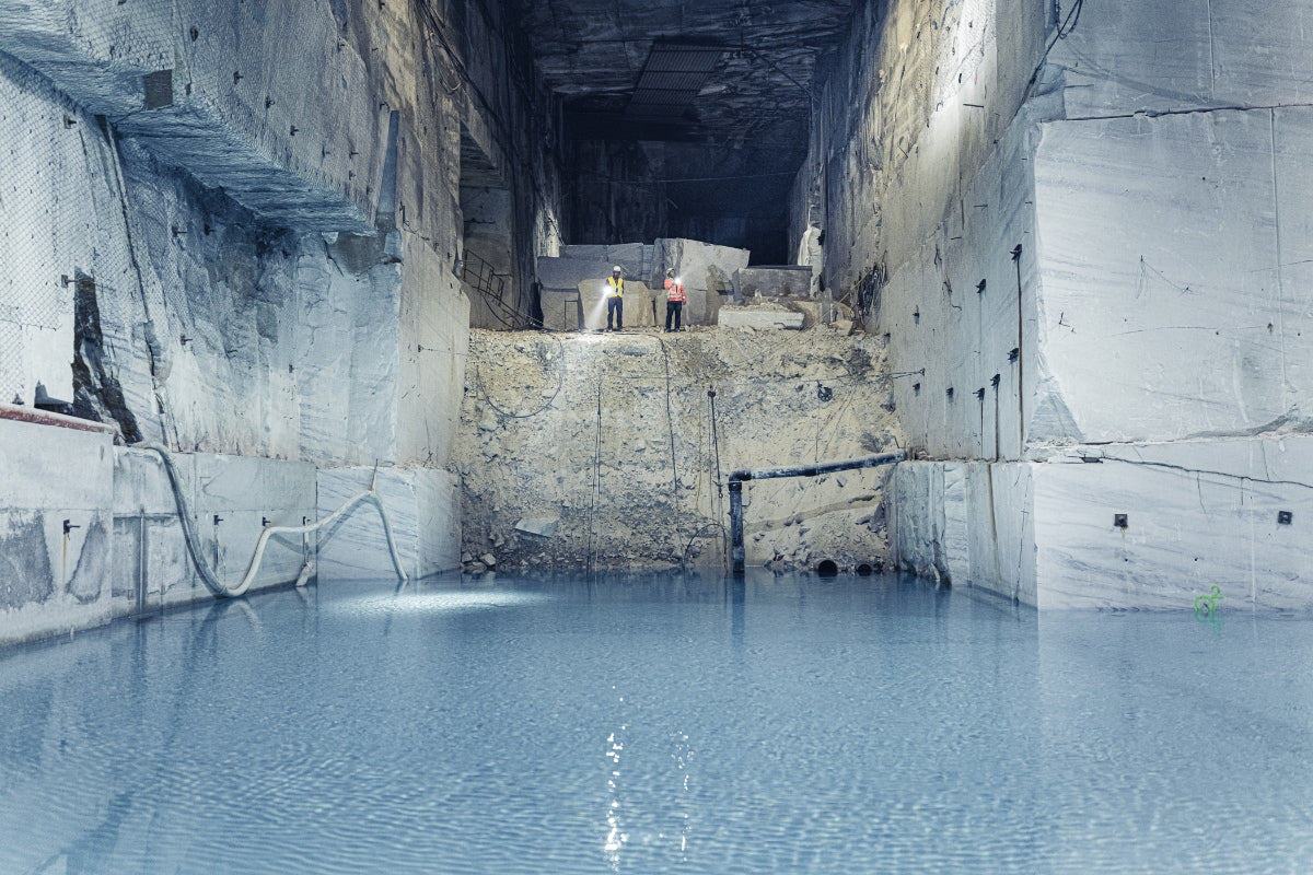 Ledlenser P21R Torch in a quarry scene with two workers in safety vests on a ledge above a water filled opening