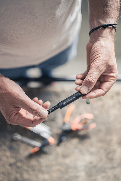 P2R Torch held horizontally in hands outdoors compact black rechargeable pen light being assembled adjusted