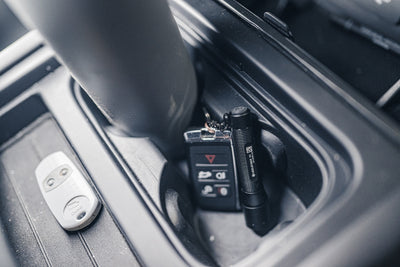 Ledlenser P3 Torch shown upright in car centre console storage with a key fob nearby