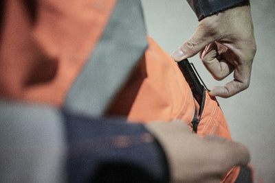 Ledlenser P4R Torch close up of a person adjusting a strap on an orange high visibility jacket