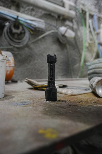 Ledlenser P5R Pro Torch standing upright on a dusty workbench at a construction site with blurred tools in the background