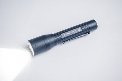 Ledlenser P5 Torch lying on a white surface with a beam of light projecting to the left