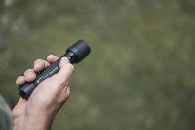 Ledlenser P7R Pro Torch held in a hand outdoors showing a black compact flashlight with textured grip