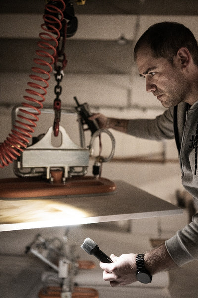 Ledlenser P7R Pro Torch held by a technician in a workshop bench lighting in foreground with a red coiled hose in the background
