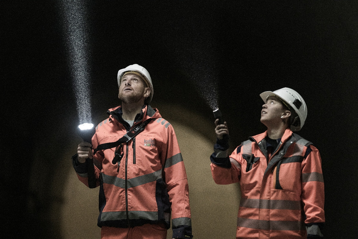 P7R Pro Torch held by a worker in orange safety jacket and white helmet in a dark tunnel with beam illumination