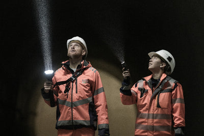 P7R Pro Torch held by a worker in orange safety jacket and white helmet in a dark tunnel with beam illumination