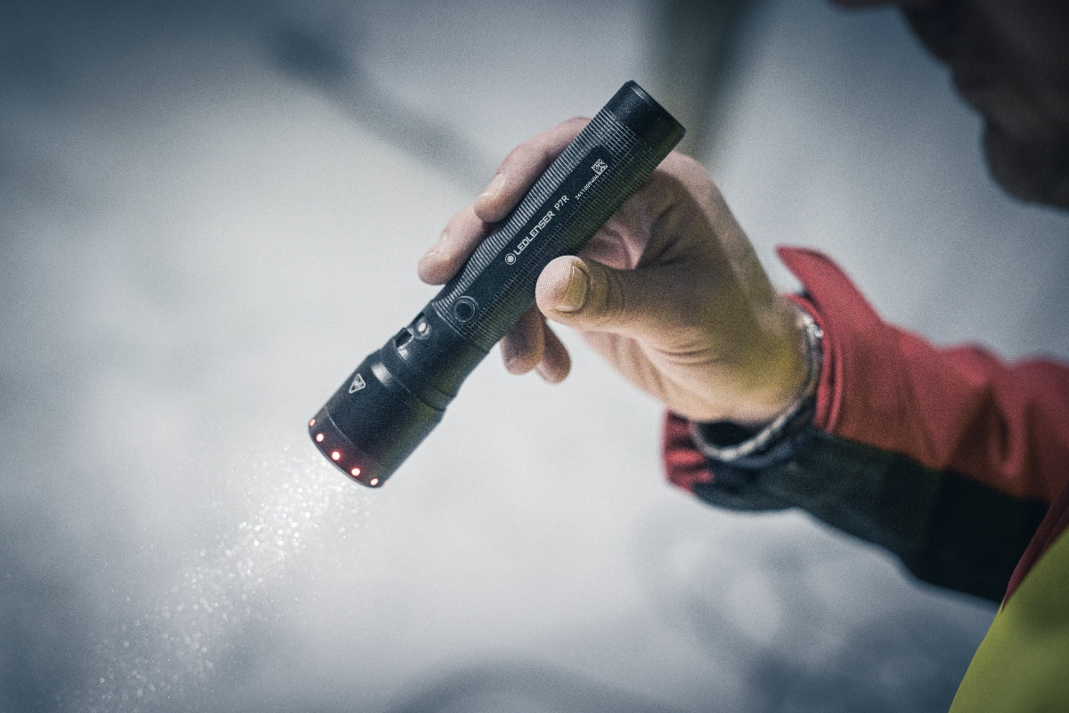 P7R Torch held in a right hand a black compact Ledlenser flashlight with red indicator lights at the base in use
