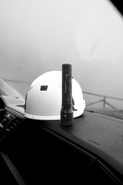 P7R Torch standing upright on a car dash with a white helmet in the background