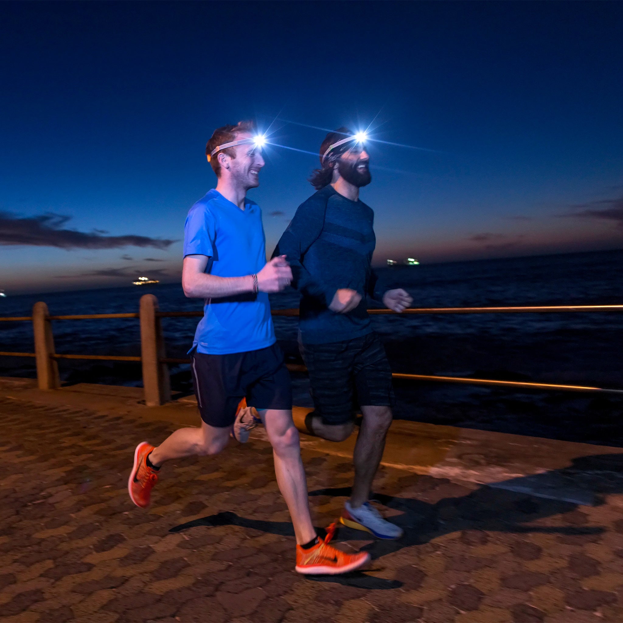 NEO Blue Battery Operated Headlamp worn by a runner; two men jogging on a waterfront promenade at dusk