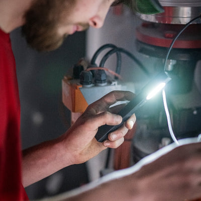 W2R Work Pen and Test Light held by a technician a compact black pen‑style LED torch emitting bright light beside electrical equipment