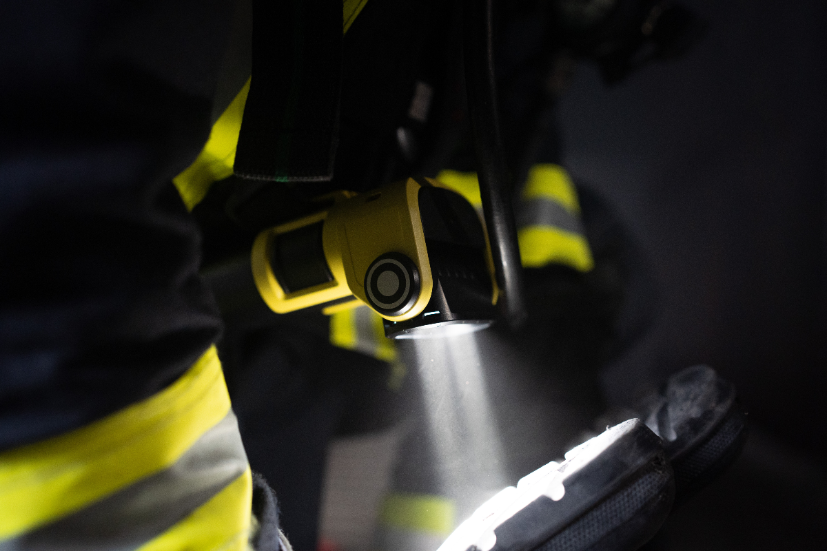 EXC6R Light rechargeable right angle torch mounted on a firefighter in high‑visibility gear beam shining on a boot