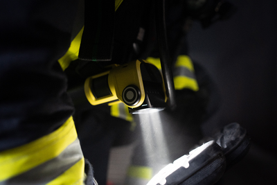 EXC6R Light rechargeable right angle torch mounted on a firefighter in high‑visibility gear beam shining on a boot