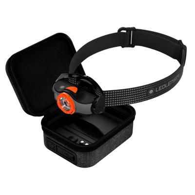 MH5 Powercase Combo headlamp with orange bezel on a black elastic headband beside the protective charging case
