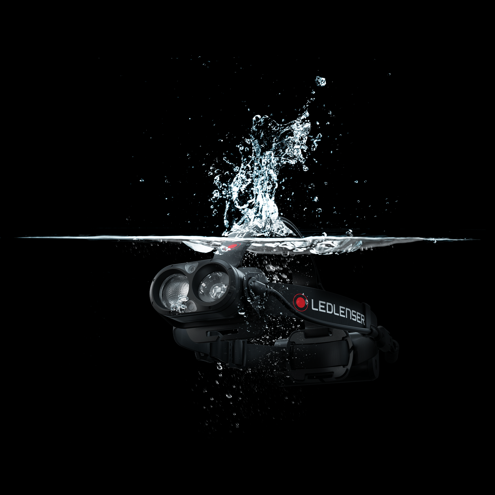 Ledlenser H19R Core Headlamp with dual front lamps and black headband partially submerged with water splashes on a black background