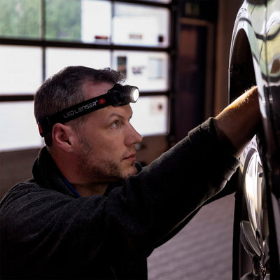 Ledlenser H7R 2 Headlamp worn by a man in a workshop adjusting a vehicle wheel with the headlamp on