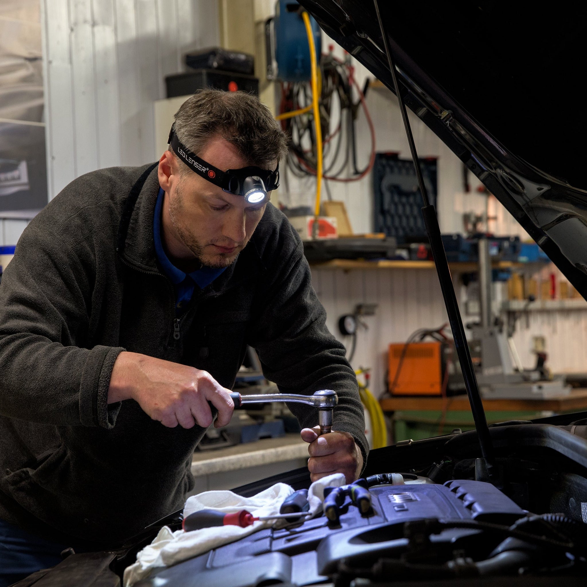 H7R 2 Headlamp worn by mechanic in a workshop illuminating the car engine bay with a Ledlenser headlamp